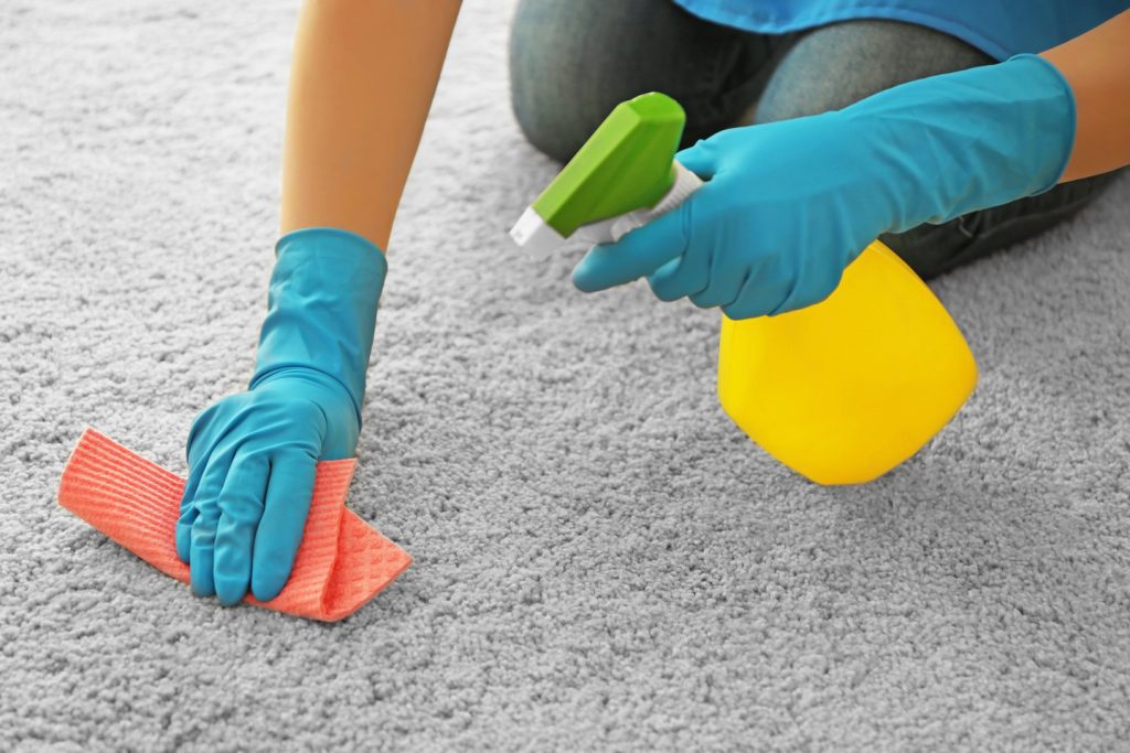 Woman cleaning carpet with detergent and napkin, closeup